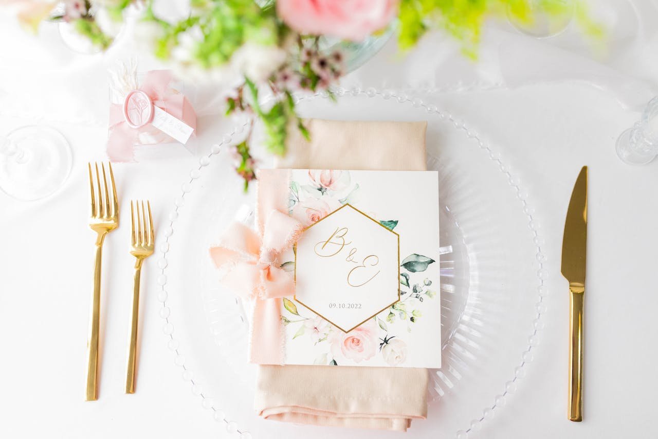 Chic wedding table setup featuring floral invitation, gold cutlery, and delicate décor.